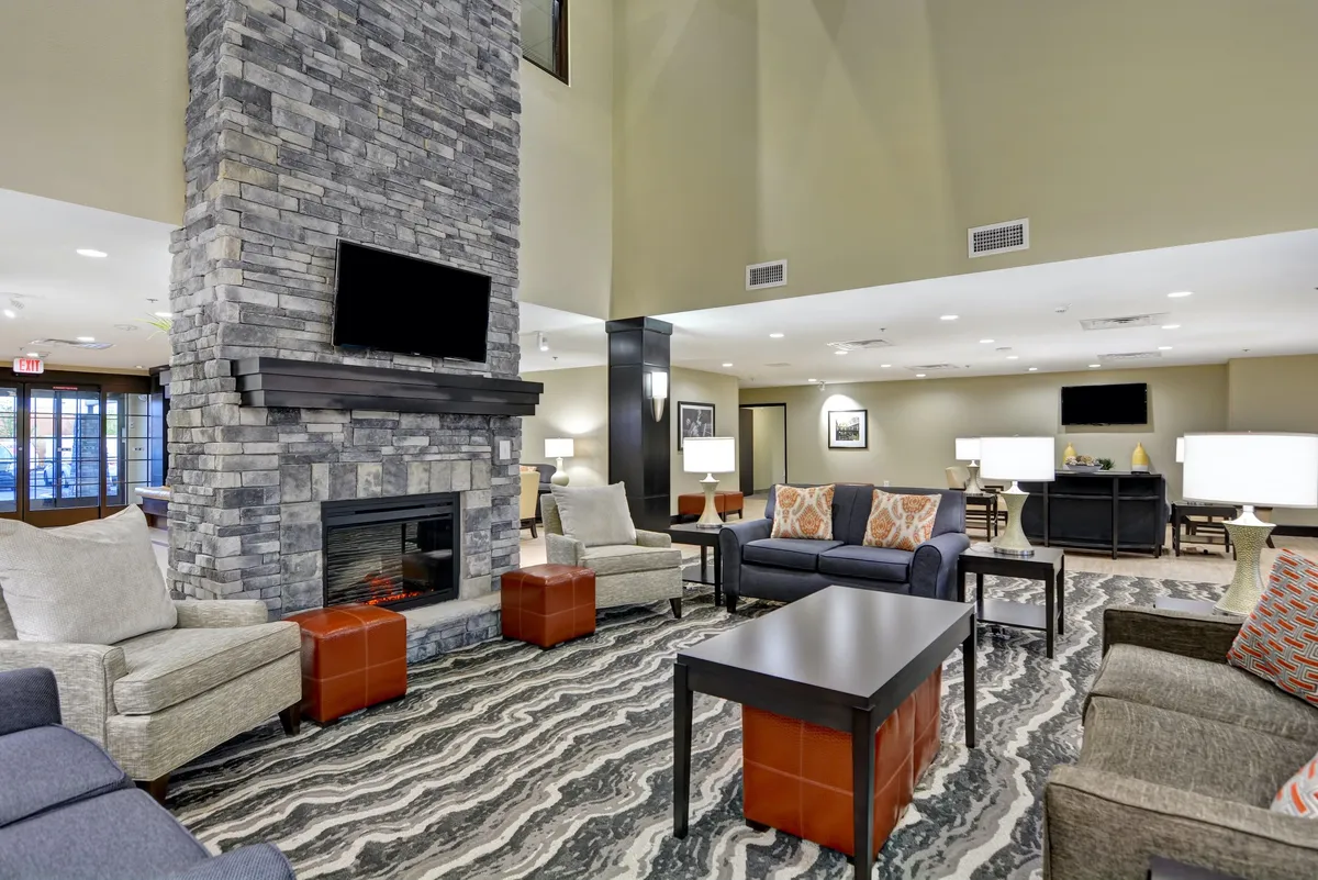 A communal living area centered around a stone fireplace, with comfortable seating, a stylish coffee table, and decorative pillows. The scene is set for socializing, reading, or enjoying family gatherings, and exudes a warm, communal vibe.